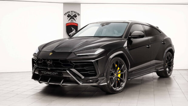 Black Lamborghini Urus with carbon fiber details parked in a modern showroom interior