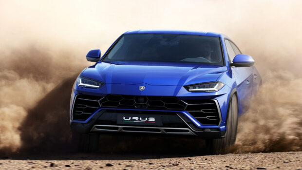 Blue Lamborghini Urus driving fast on dusty road with a driver inside