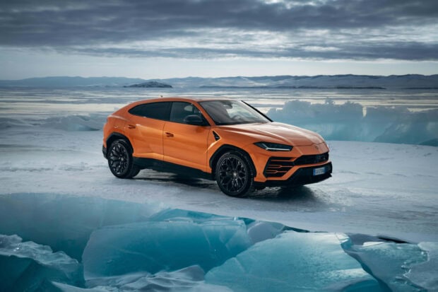 Orange Lamborghini Urus parked on icy terrain with glacial landscape in background