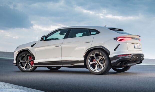 White Lamborghini Urus SUV side view with red brake calipers on race track