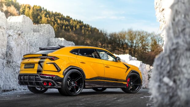 Yellow Lamborghini Urus with black details parked on the road near white rock walls