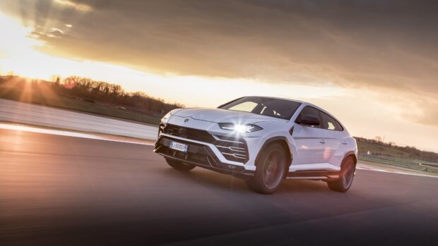 White Lamborghini Urus driving fast on the track during sunset with motion blur