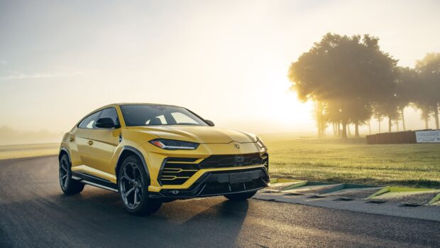 Yellow Lamborghini Urus on a racetrack at sunrise