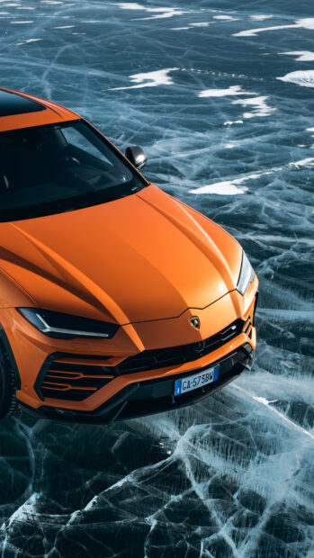 Orange Lamborghini Urus driving on cracked ice in winter scenery with high detail