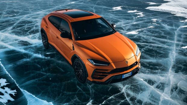 Orange Lamborghini Urus parked on cracked ice with sleek design and sharp headlights