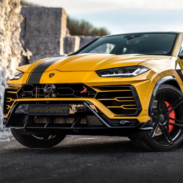 Yellow Lamborghini Urus with black racing stripes parked on road