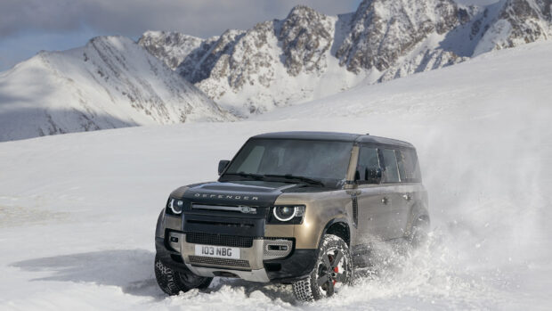 Land Rover Defender driving through snowy mountain terrain with high quality and rugged performance