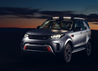 A Land Rover Discovery vehicle parked during sunset with illuminated headlights