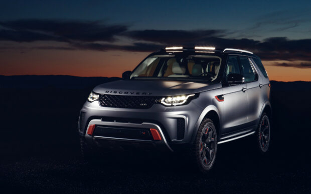 A Land Rover Discovery vehicle parked during sunset with illuminated headlights