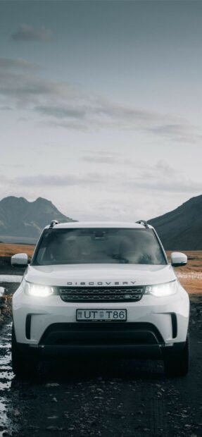 White Land Rover Discovery on a rocky road with mountain background