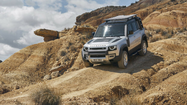 Land Rover driving on a rugged dirt trail in a rocky desert terrain