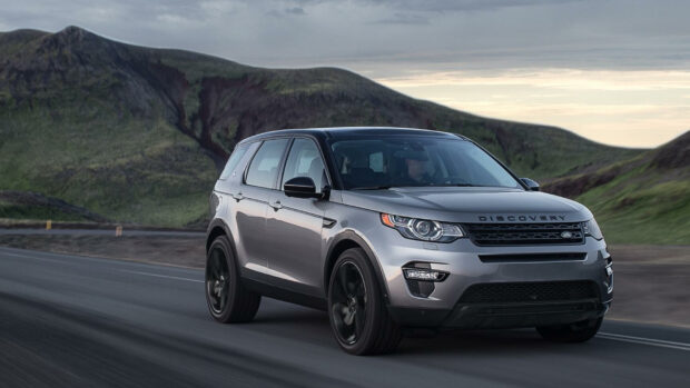 A Land Rover Discovery driving on a mountain road during the evening light