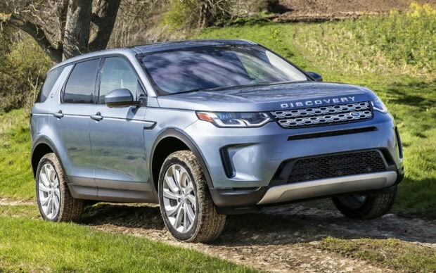 A Land Rover Discovery SUV parked on a dirt path surrounded by green grass