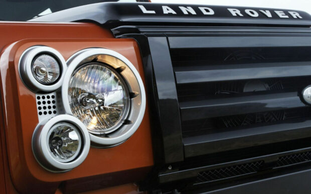 Close up of Land Rover front headlight and grille on an orange vehicle