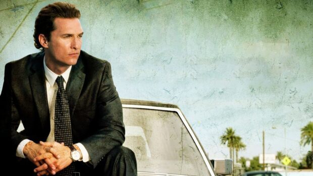 Lawyer sitting thoughtfully in a suit by a white car in an outdoor setting