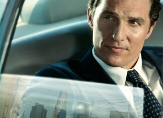 A confident lawyer sitting inside a car looking outside the window with a cityscape reflection