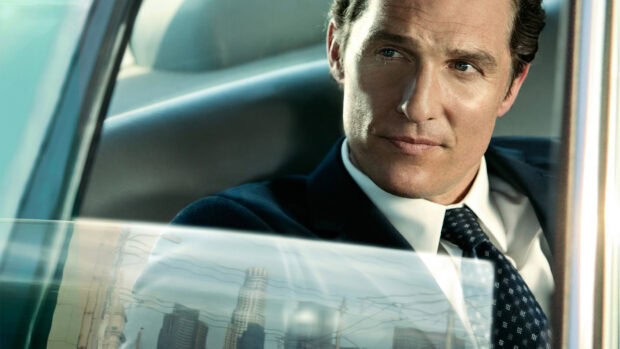 A confident lawyer sitting inside a car looking outside the window with a cityscape reflection