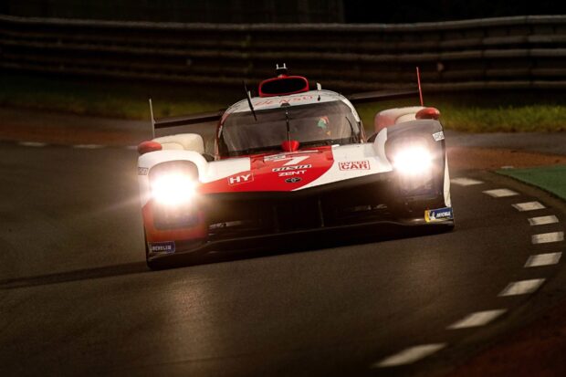 Racing car at Le Mans track with headlights on during night race