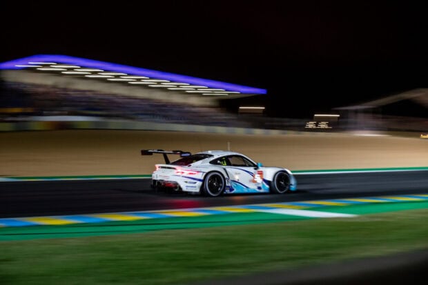 Racing car competing at Le Mans circuit at night with motion blur