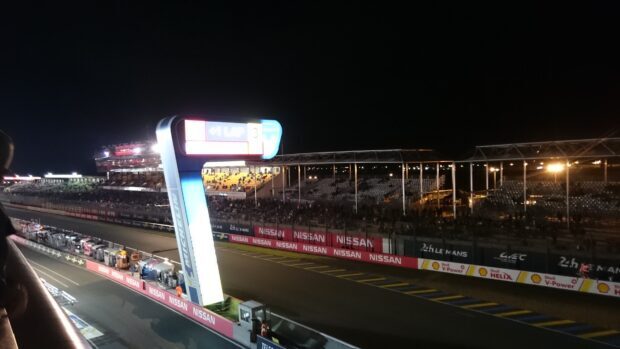 Le Mans race track at night with grandstands and pit lane illuminated