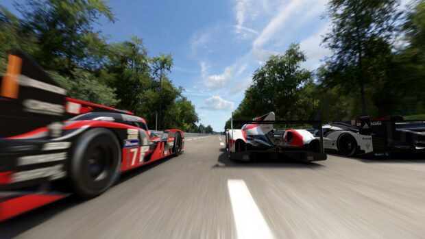Racing cars competing fiercely on Le Mans track with green trees and blue sky