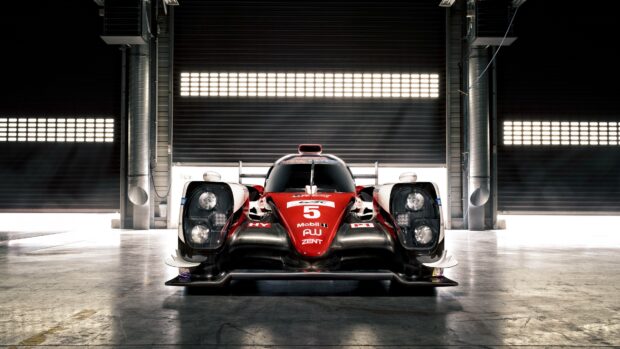 Red and white Le Mans racing car parked inside a garage bay