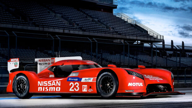 Red Nissan Nismo race car on Le Mans track under cloudy sky