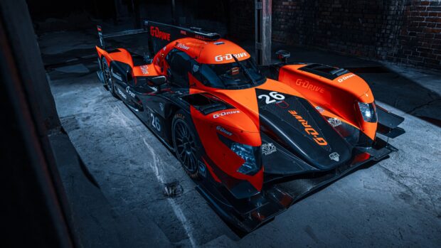 A racing car with G Drive branding at Le Mans in a dark garage setting