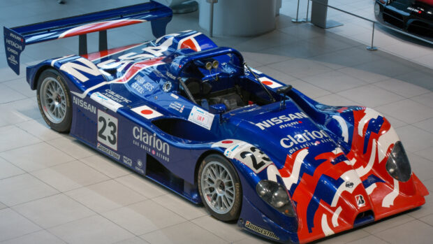 Blue Nissan Le Mans race car number 23 with red and white stripes in a showroom