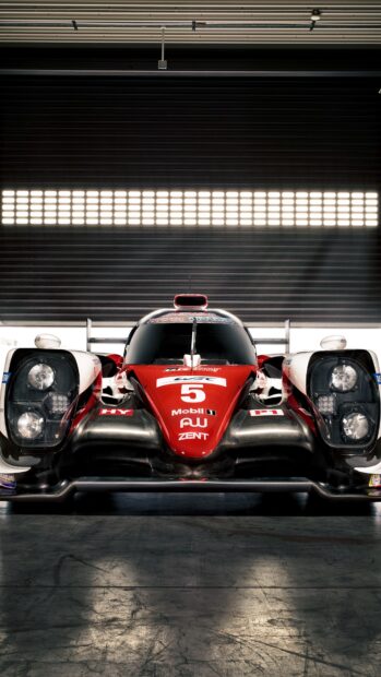 A Le Mans race car hybrid prototype in a garage with detailed front view headlights and aerodynamic design