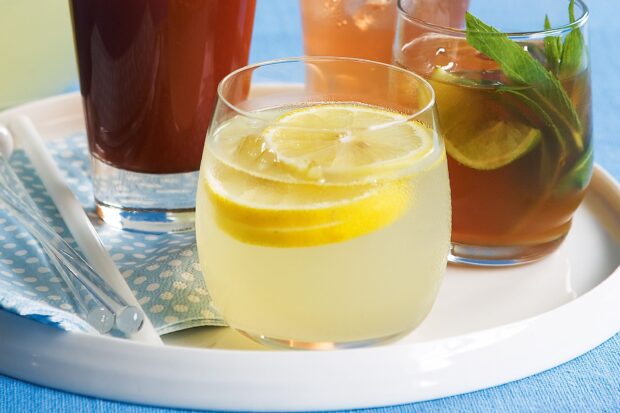 A refreshing lemonade drink with lemon slices served in a glass on a tray