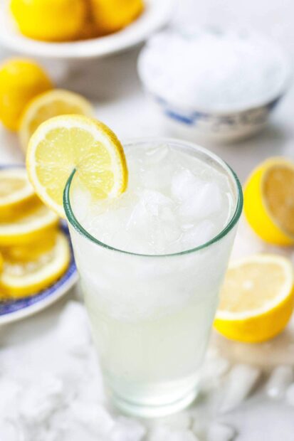 A refreshing glass of lemonade with lemon slices and ice cubes on a bright surface