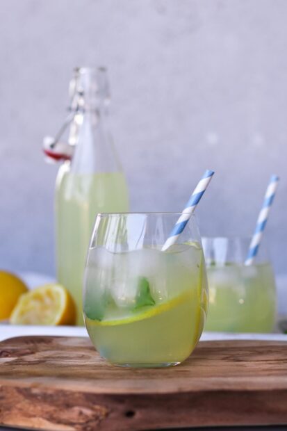 A refreshing glass of lemonade with ice and a striped straw on a wooden surface