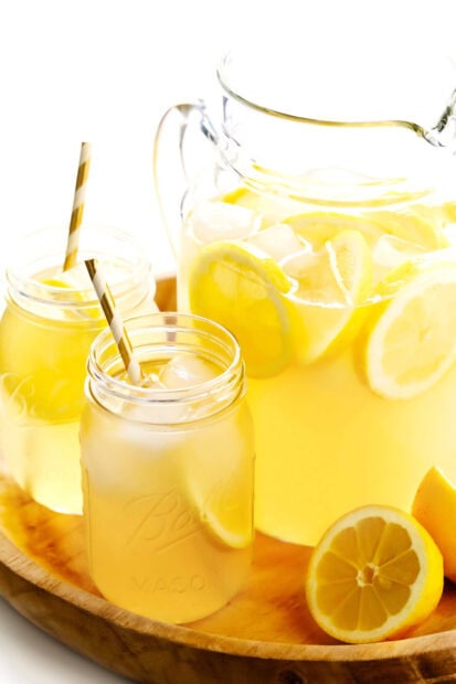 Refreshing lemonade with lemon slices and ice in mason jars on a wooden tray
