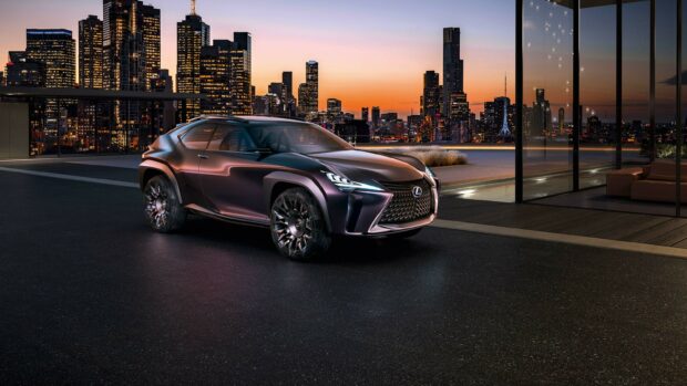 A sleek Lexus parked outside a modern building with a city skyline at sunset in the background