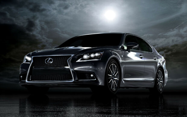 A sleek Lexus sedan with shining headlights under a moonlit cloudy sky