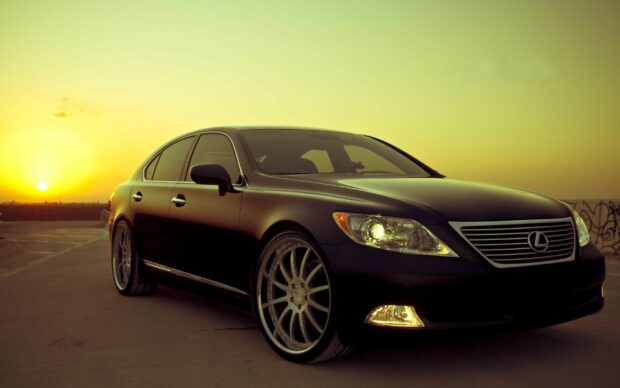 Black Lexus car parked at sunset with glowing headlights and detailed wheels
