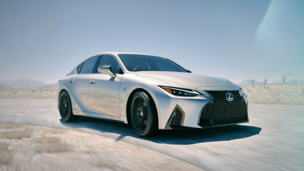 A silver Lexus sedan driving fast on a desert road with mountains in the background