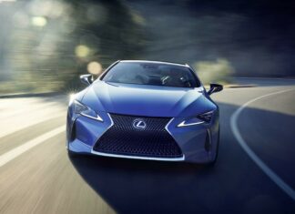 Blue Lexus driving on a winding road with sunlight reflecting on the car surface