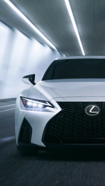 Front view of a sleek Lexus car driving through a tunnel with illuminated headlights