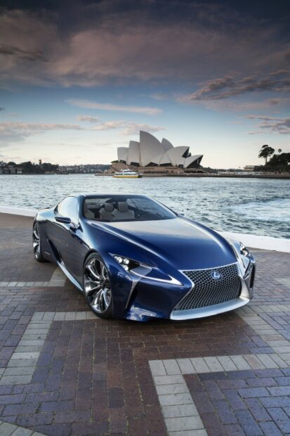 Blue Lexus sports car parked near waterfront with Opera House in background