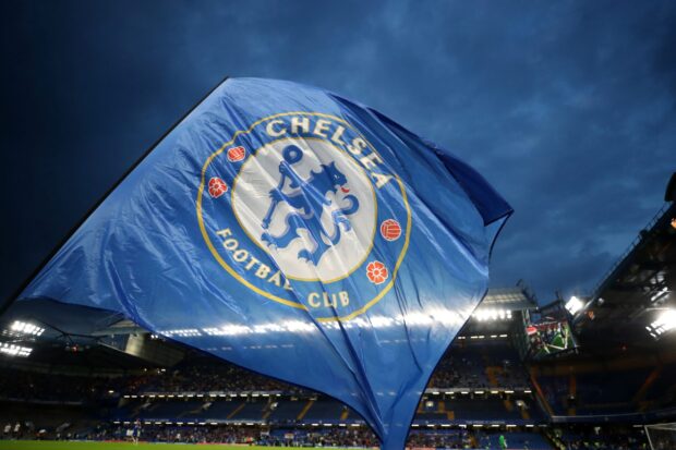 Chelsea logo waving on a large blue flag at a football stadium during a match