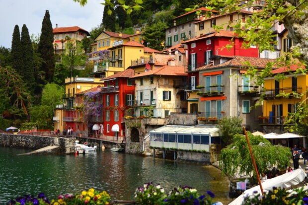 Colorful buildings by the lakeside in Lombardy surrounded by lush greenery and flowers