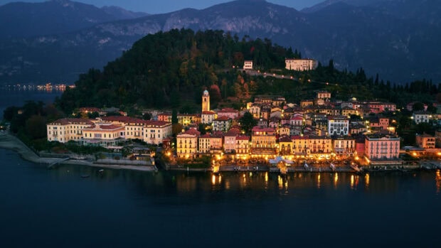 Beautiful night view of Lombardy town with illuminated buildings and lake reflections
