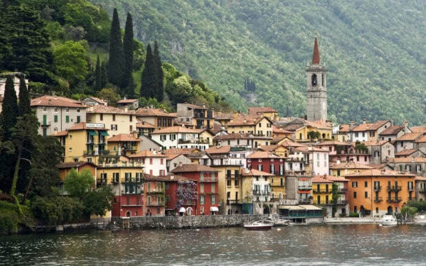 Colorful town buildings near lake at Lombardy surrounded by lush green mountains