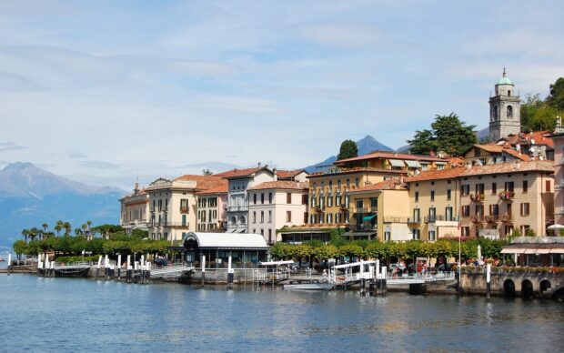 Historical buildings and waterfront in Lombardy with mountains in the background