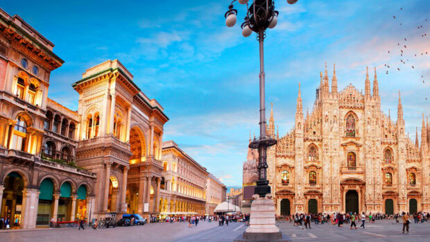The grand cathedral and historic buildings in Lombardy with a clear blue sky and bustling square