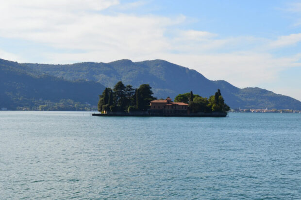 A serene Lombardy island with lush trees and a villa surrounded by calm lake waters