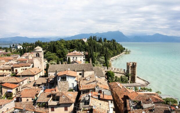 A scenic view of Lombardy town rooftops and lush greenery near the lake