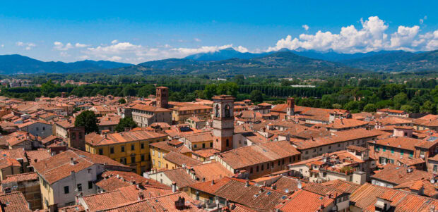 A panoramic view of Lucca Italy skyline with historic buildings and surrounding hills under a clear blue sky